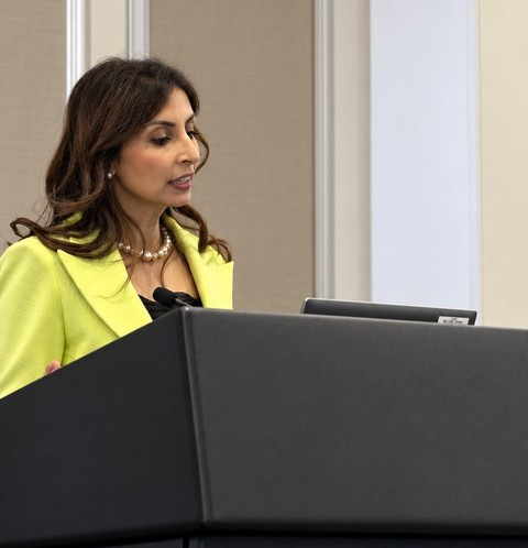 Speaker in a bright jacket presenting at the lectern